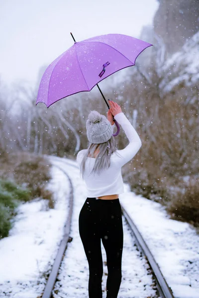 눈내리는 모자를 자주색 우산을 알아볼 수없는 소녀의 — 스톡 사진