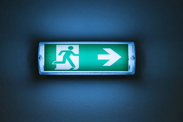 An isolated shot of an Emergency Exit sign on the blue wall