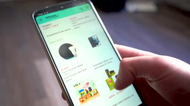 Una Mano Scorre Attraverso Amazon Gamma Prodotti Uno Smartphone Shopping — Video Stock