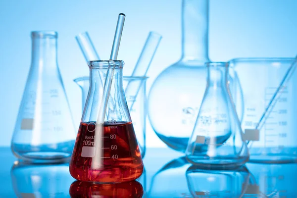 Különböző Üveglombikok Laboratóriumi Berendezések Vörös Folyadékkal Asztalon — Stock Fotó