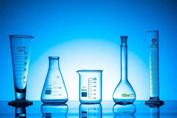 Eine Vielzahl Von Glasflaschen Und Laborgeräten Auf Blauem Hintergrund — Stockfoto