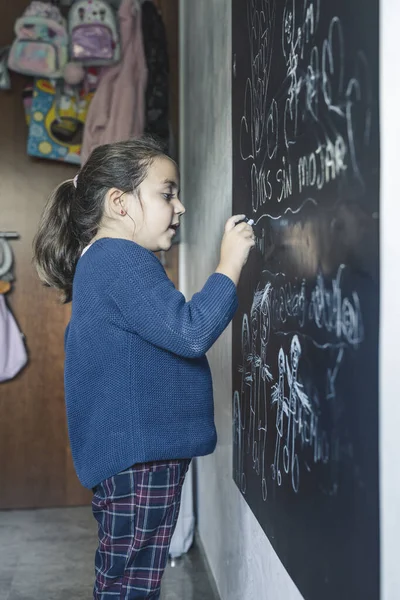 Vertical Shot Cute Caucasian Little Girl Drawing Blackboard Chalk Her — стоковое фото