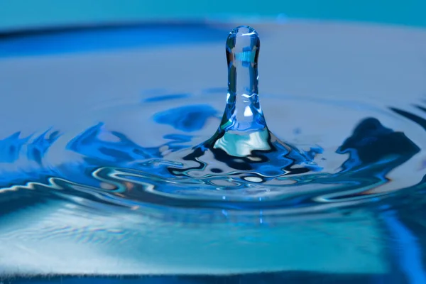 一张令人惊奇的水蓝色背景上的水滴弹跳的照片 — 图库照片