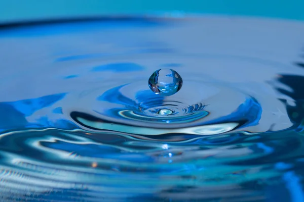 Incrível Tiro Uma Gota Saltando Sobre Água Fundo Azul — Fotografia de Stock