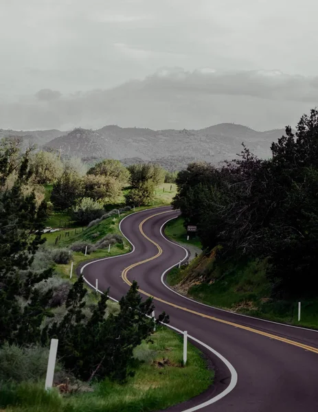 Tiro Vertical Uma Estrada Curvilínea Com Montanhas Florestadas Fundo — Fotografia de Stock