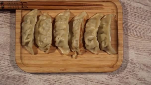 Holzschneidebrett Mit Chinesischen Knödeln Und Essstäbchen Von Oben — Stockvideo