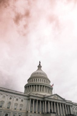 A vertical shot of the United States Capitol in Washington, DC, against the cloudy sky clipart