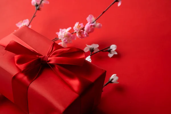 红色礼品盒特写照片 内附彩带和红色背景的花朵 — 图库照片