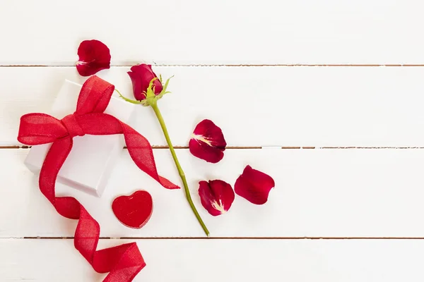 情人节那天 红玫瑰花瓣和一个有蝴蝶结的礼品盒 — 图库照片