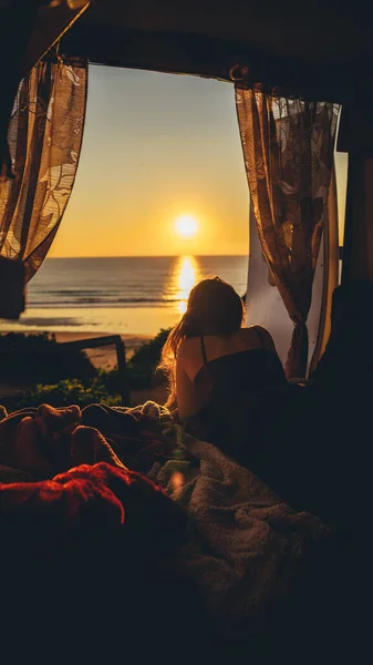 日没の間にビーチの近くに横たわってリラックスした女性の垂直ショット — ストック写真