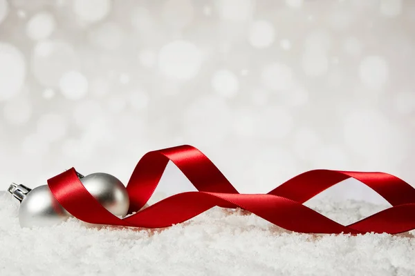 背景がぼやけている偽の雪の上に赤いリボンを持つクリスマスの装飾品の閉鎖 — ストック写真