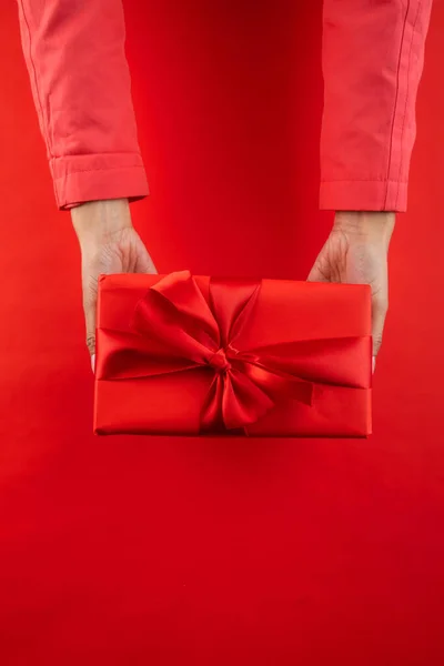Vertikal Bild Kvinnliga Händer Håller Röd Presentförpackning Isolerad Röd Bakgrund — Stockfoto
