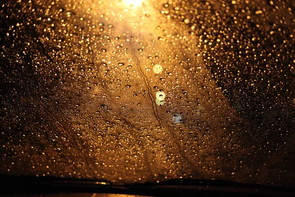 Zbliżenie Ujęcia Kropel Deszczu Przedniej Szybie Samochodu Jasnym Światłem Ulicznym — Zdjęcie stockowe