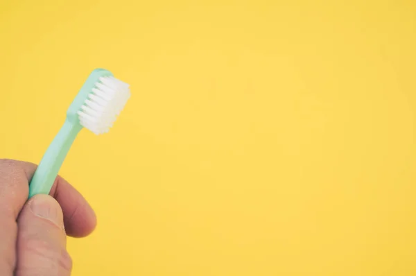 Closeup Hand Holding Toothbrush Isolated Yellow Background Empty Space Text — Stock Photo, Image