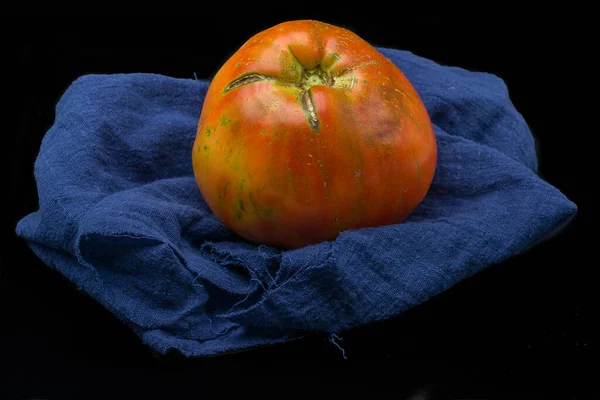 Close Tomate Muito Grande Pano Azul Isolado Fundo Preto — Fotografia de Stock