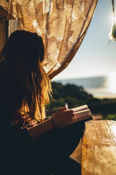 日没の間にビーチで本を読んでいる女性の垂直ショット — ストック写真
