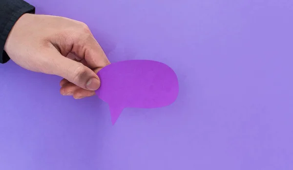 Uma Mão Masculina Segurando Cartão Forma Balão Fala Fundo Violeta — Fotografia de Stock