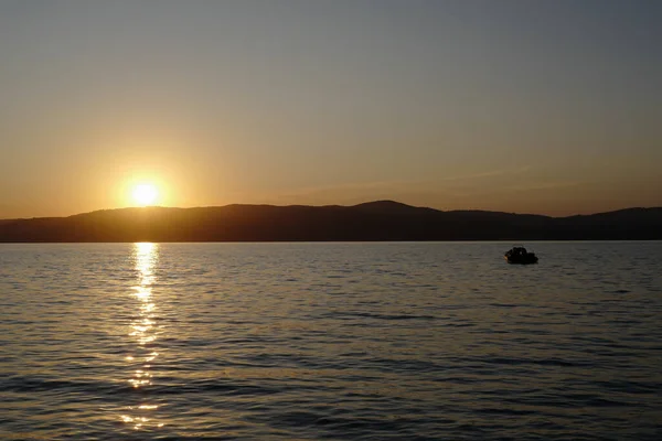 Sebuah Perahu Danau Dikelilingi Oleh Bukit Bukit Selama Matahari Terbenam — Stok Foto