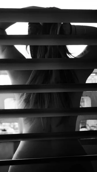 窓の後ろにいる謎の魅力的な女性の裸の背中の灰色のスケール — ストック写真