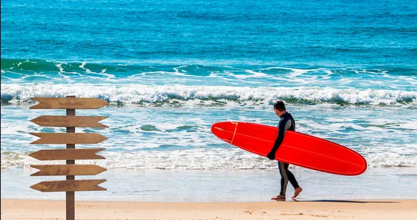 ビーチにサーフボードを持つサーファーとブラジルのコピースペースを持つ木製の看板 — ストック写真