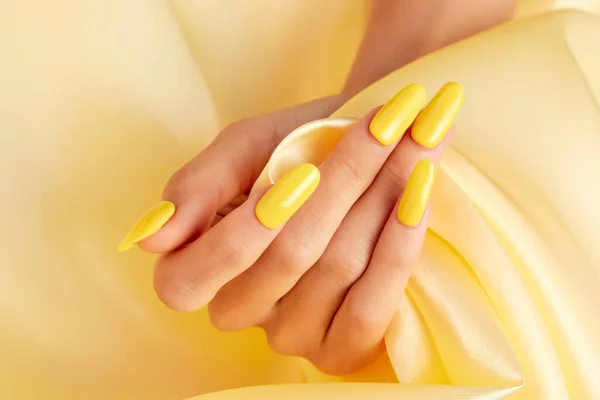 Closeup Shot Female Hand Yellow Nail Polish Yellow Silk Fabric — Stock Photo, Image