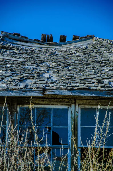 在阳光灿烂的日子拍摄的田野里一座废弃的老房子废墟的垂直镜头 — 图库照片