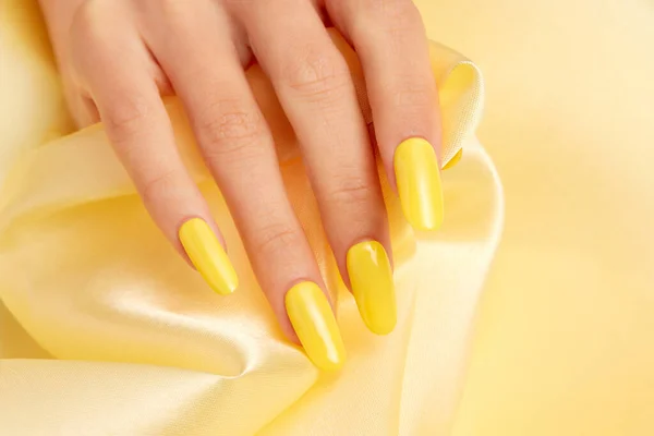 Κοντινό Πλάνο Γυναικείου Χεριού Κίτρινο Βερνίκι Νυχιών Κίτρινο Μεταξωτό Ύφασμα — Φωτογραφία Αρχείου