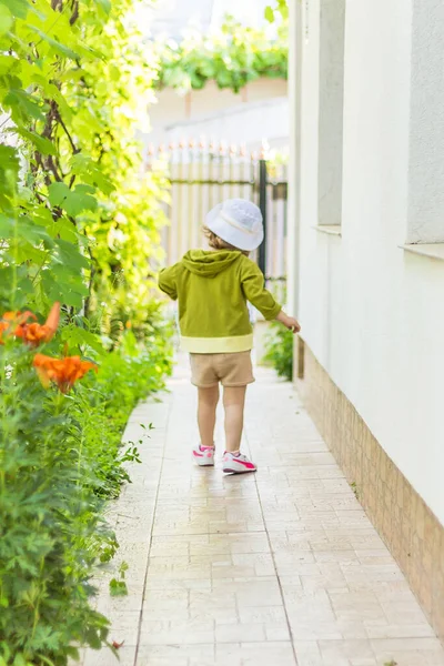 庭に白い帽子をかぶった素敵な子供の垂直ショット — ストック写真