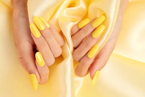 Closeup Shot Female Hands Yellow Nail Polish Yellow Silk Fabric — Stock Photo, Image