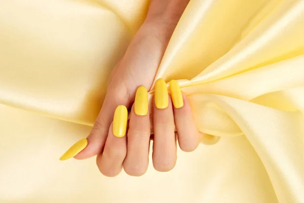 Κοντινό Πλάνο Γυναικείου Χεριού Κίτρινο Βερνίκι Νυχιών Κίτρινο Μεταξωτό Ύφασμα — Φωτογραφία Αρχείου