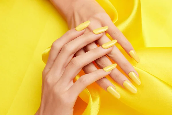 Closeup Shot Female Hands Yellow Nail Polish Yellow Silk Fabric — Stock Photo, Image