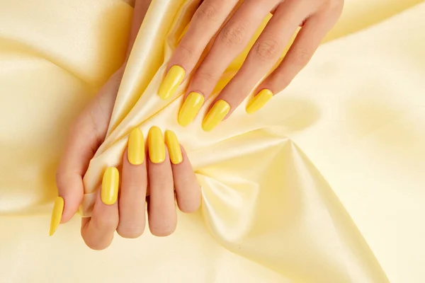 Κοντινό Πλάνο Γυναικείων Χεριών Κίτρινο Βερνίκι Νυχιών Κίτρινο Μεταξωτό Ύφασμα — Φωτογραφία Αρχείου