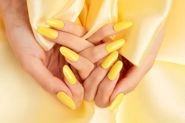 Closeup Shot Female Hands Yellow Nail Polish Yellow Silk Fabric — Stock Photo, Image