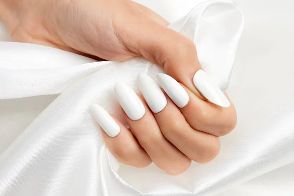 Tiro Close Mão Uma Fêmea Com Esmalte Branco Tecido Seda — Fotografia de Stock