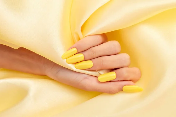 Tiro Close Mão Uma Fêmea Com Esmalte Amarelo Tecido Seda — Fotografia de Stock