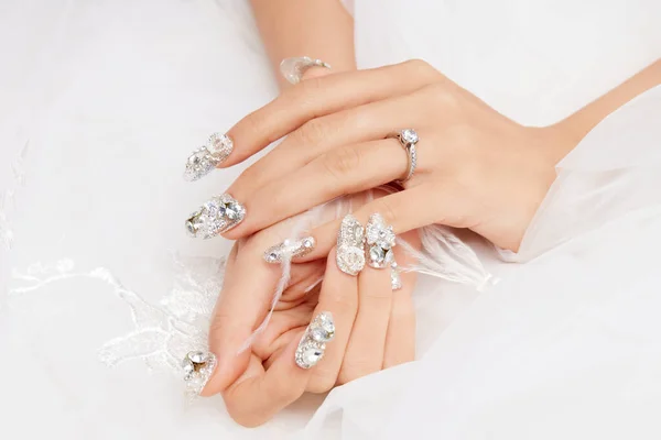 A closeup shot of a female\'s hands with diamonds on the nails