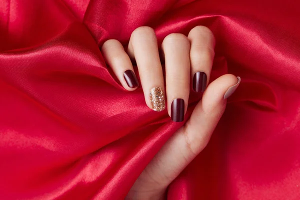 赤い絹の生地を愛撫美しいネイルポリッシュで女性の手のクローズアップショット — ストック写真