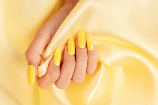 Tiro Close Mão Uma Fêmea Com Esmalte Amarelo Tecido Seda — Fotografia de Stock