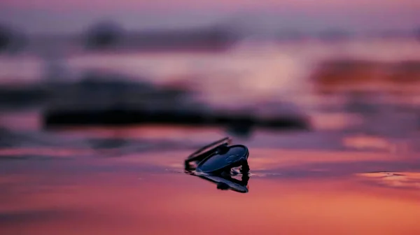 夕日の海の紫色の水の中でサングラスのクローズアップショット — ストック写真