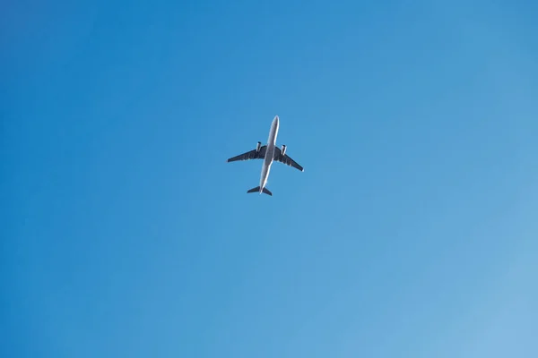 青い空と太陽の下を飛行する飛行機の低角度ショット — ストック写真