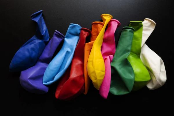 stock image A top view closeup of various not yet inflated colorful balloons on a shiny black background