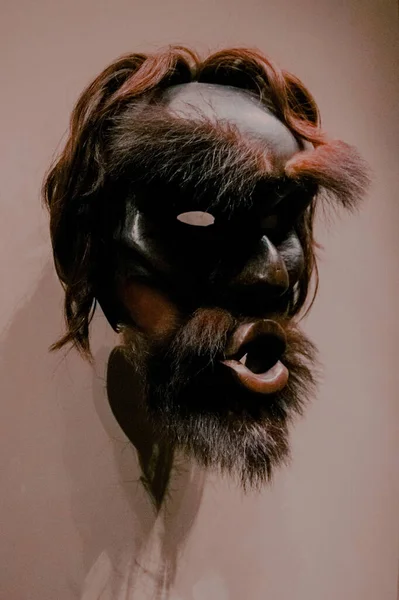 ベージュの壁の背景に吊るされた恐ろしい木製のマスク — ストック写真