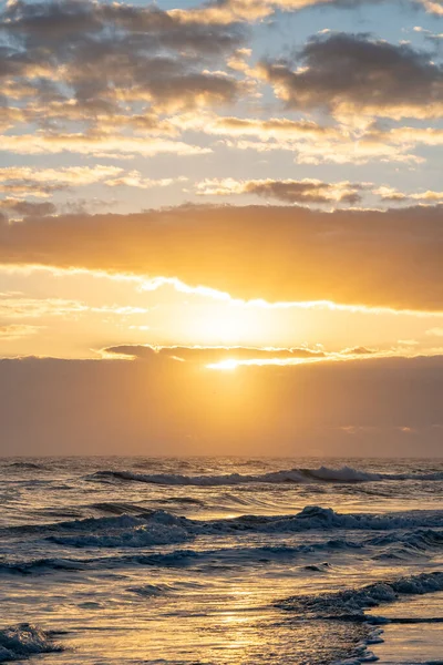 A vertical beautiful shot of ocean waves at sunset