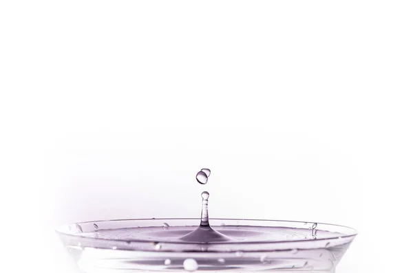 水滴在水杯中产生涟漪 呈紫色 与白色背景隔离 — 图库照片