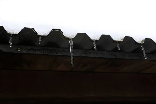 冰柱悬挂在屋顶边缘的低角度冰柱和雪 — 图库照片