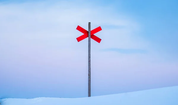 A ski trail red cross sign in the snowy area