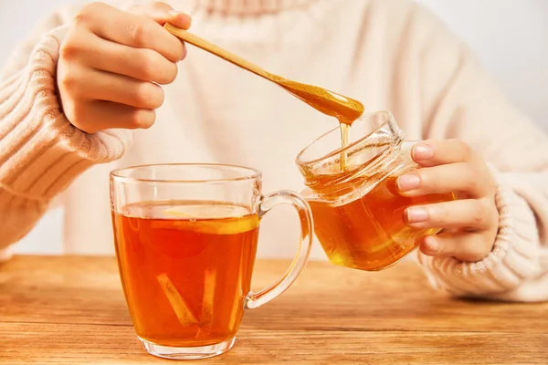レモンと生姜と熱いお茶のカップに蜂蜜を注ぐ女性 寒さに対する有機治療 — ストック写真