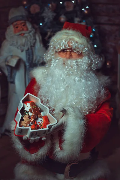サンタクロースの衣装を着た白人男性がお菓子入りの箱を持っている — ストック写真
