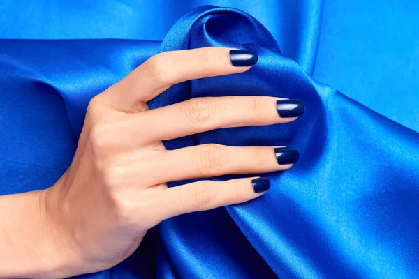 Uma Mão Feminina Com Unhas Azuis Segurando Tecido Cetim Azul — Fotografia de Stock