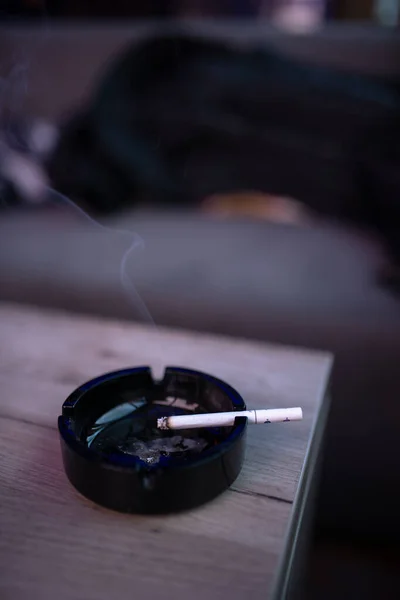 木のテーブルの上の灰皿のタバコの垂直ショット — ストック写真